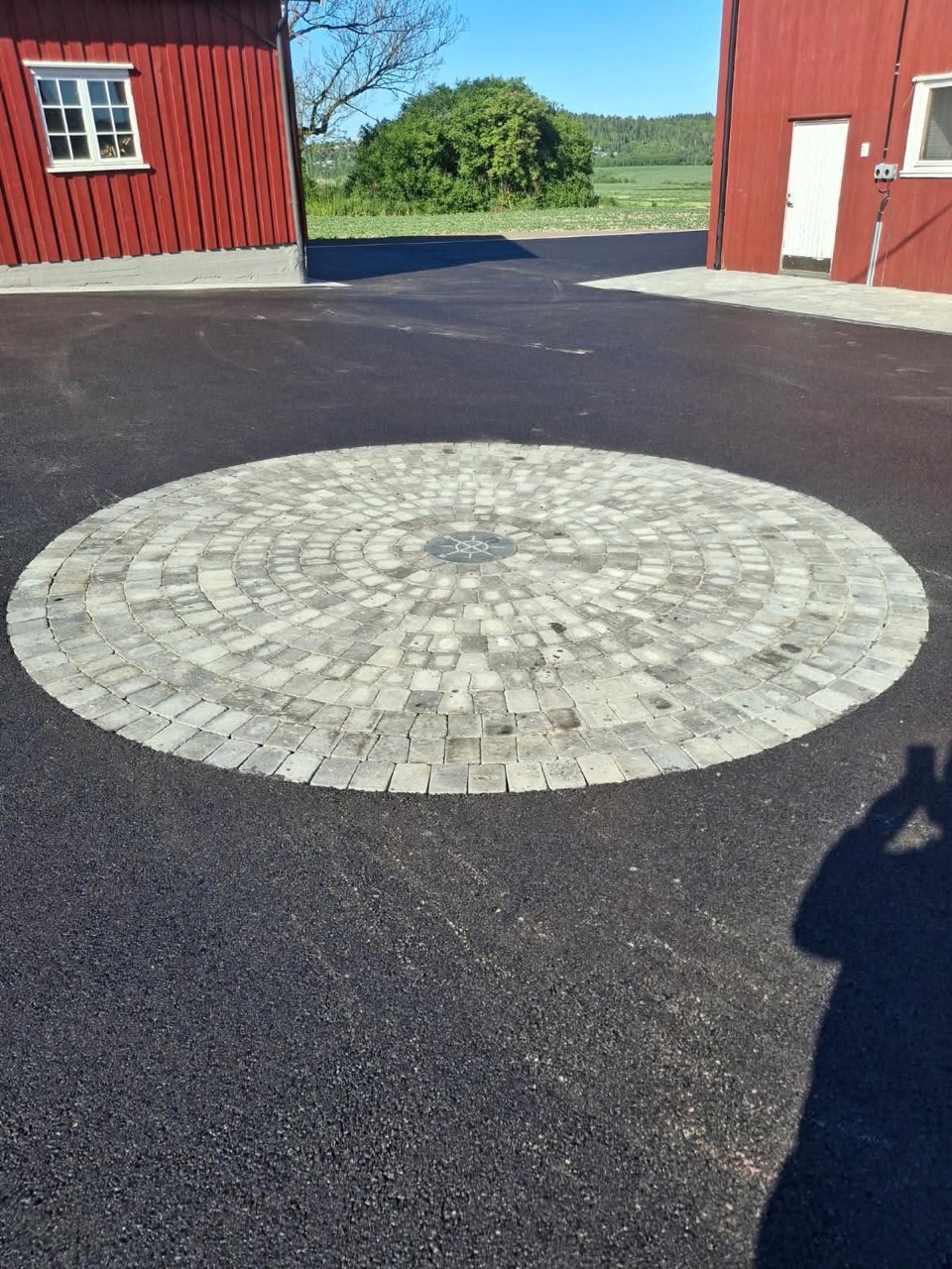 Asfaltert gårdsplass med et sirkelformet felt i belegningsstein